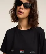 Remera negra alargada de algodón, con cuello redondo y mangas cortas. Estampa en la espalda con la palabra "TOKYO" en rojo y "JAPAN" en celeste, sobre una fotografía en blanco y negro de una calle de Tokio.
