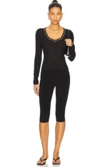 Top de manga larga ajustado de punto ligero tipo pointelle, color blanco, con escote en V ribeteado con encaje negro y blanco.