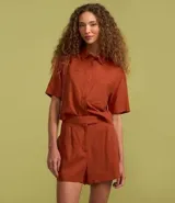 Short corto color beige confeccionado en viscosa y lino, con cierre lateral desplazado, pliegues delanteros y bolsillos laterales.