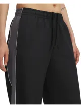 Pantalón deportivo Under Armour Rival Woven para mujer, color negro con detalles en gris y logo blanco.