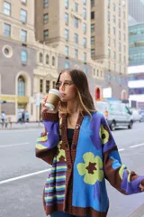 Cárdigan de punto con estampado floral en tonos celeste, verde, marrón y violeta. Tiene corte oversized y cierre frontal con botones.