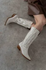 Bota de caña media color marrón con bordados decorativos en hilo color crema, puntera en punta y taco de madera.