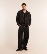 Pantalón masculino de jeans azul oscuro con efecto lavado, corte super baggy, cintura con trabillas, cierre tradicional, bolsillos y detalles de desgaste.