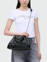 Bolso negro de cuero con textura granulada, con el nombre de la marca grabado en relieve en el frente. Tiene doble asa corta superior y una correa larga de cadena plateada con aplique de cuero en el hombro.
