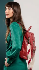 Mochila negra de símil cuero con apertura superior y tres bolsillos frontales con cierres metálicos. Incluye bolsillos laterales y tres bolsillos internos. Tiene correa larga de galón regulable para usar como bandolera y correas para colgar en la espalda.
