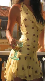 Vestido corto amarillo con lunares marrones, escote drapeado y tirantes finos.