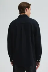 Camisa negra de algodón Oxford con cuello americano, tapeta clásica, bolsillo superior abierto y canesú en la espalda. Mangas largas con puños abotonados y bajo levemente redondeado. Corte estándar para una silueta clásica y cómoda.