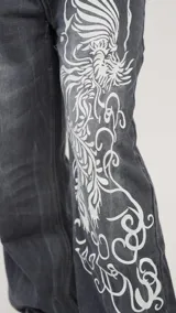 Pantalón de jean azul con estampado de un dragón blanco en la pierna derecha, corte recto y tiro bajo.