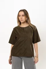 Remera color verde militar de gamuza, con cuello redondo, mangas cortas y detalle de cordones ajustables en el ruedo.