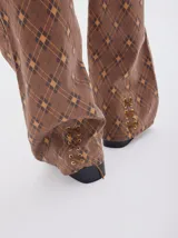 Jean wide leg color marrón con estampado de rombos en tonos beige y azul. Incluye un cinturón integrado en la pretina con hebilla metálica.