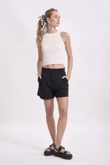 Musculosa negra de tejido de punto acanalado, con cuello redondo y sisas amplias.