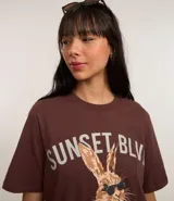 Remera marrón de algodón con cuello redondo y mangas cortas. Estampa frontal de un conejo con gafas de sol y texto "Sunset Blvd. Los Angeles California".