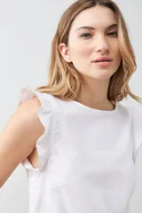 Blusa blanca sin mangas de lino con cuello redondo y volados en los hombros.