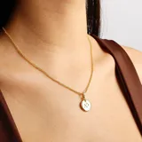 Collar dorado con cadena fina y dije redondo blanco con el signo de sagitario en dorado.