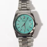 Reloj de pulsera plateado con esfera color turquesa y correa de eslabones metálicos.