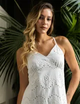 Vestido blanco de broderie con escote en V, corte bajo el busto y breteles finos cruzados en la espalda. Tiene forro interno a tono y largo midi.