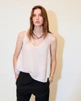 Top sin mangas de lino color blanco, con escote redondo, corte en A, ruedo asimétrico y recortes laterales.