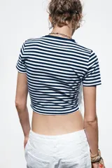 Camiseta corta a rayas horizontales blancas y azul marino, de algodón, con cuello redondo y mangas cortas.