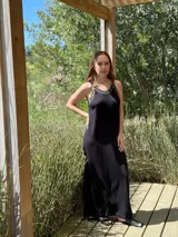 Vestido largo negro de tejido de punto, corte recto y breteles finos con ribete blanco.