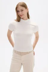Remera blanca de punto canale con cuello alto y mangas cortas.