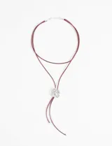 Collar de cordón negro con dije metálico plateado en forma de rosa.