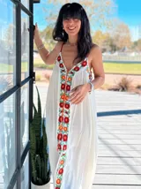 Vestido túnica blanco con bordado de flores rojas y naranjas en el frente.