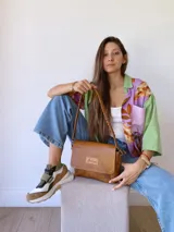 Bandolera color camel de cuero con forro de tela, correa corta con tientos y bolsillo interno.