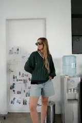 Buzo tejido verde con escote en V, cuello con rayas blancas y azul marino, y puños y ruedo con detalle de rayas.