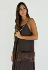 Cartera tipo sobre color marrón con textura símil piel de cocodrilo, con correa de cadena dorada.