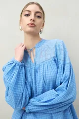 Blusa celeste con estampado a cuadros, con canesú de encaje floral, cuello mao con lazo y mangas largas abullonadas con puños elásticos.