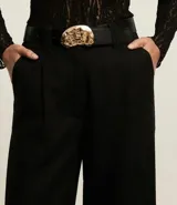 Pantalón pantalona de cintura alta, confeccionado en viscolino, con trabillas en la cintura y bolsillos falsos atrás. Incluye cinturón de material sintético con hebilla metalizada con efecto martillado.