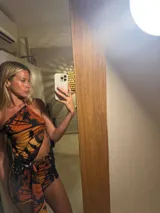 Minivestido con estampado de mariposas en tonos naranja y negro, con escote halter asimétrico y abertura en la cintura.