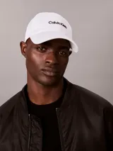 Gorra de béisbol blanca con visera curva y logotipo de Calvin Klein bordado en negro en el frente.