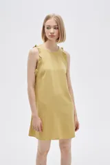 Vestido corto color crema, sin mangas, con cuello redondo y volados en los hombros.
