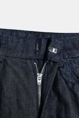 Pantalón de jean azul oscuro, de tiro alto, corte ancho tipo barrel y largo al tobillo. Cierre frontal con cremallera y botón.