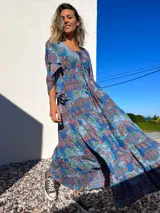 Vestido túnica largo de algodón con estampado de arabescos en tonos azules, rojos y verdes. Tiene escote en V con cordones y mangas acampanadas.