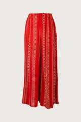 Pantalón de corte recto color rojo con estampado de cadenas doradas, pretina elástica, cierre y broche al frente, pinzas y bolsillos laterales.