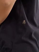 Remera negra de algodón con mangas cortas con detalle de calado y bordado en los hombros y mangas. Corte recto con cintura ajustable con cordón.