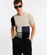 Remera masculina de punto leve, con cuello redondo y mangas cortas. Diseño con recortes en bloques de color beige, negro y azul.