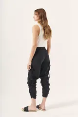 Pantalón jogger negro de nylon con elástico ancho en la cintura, puños elásticos ajustables y lazos laterales para fruncir.