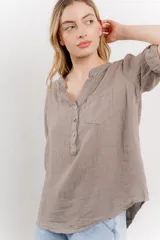 Camisa azul de lino con escote en V abotonado, bolsillo frontal y mangas 3/4 con trabilla.