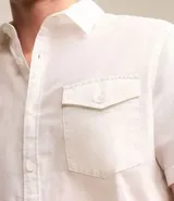 Camisa de hombre de manga corta en lino color blanco, con cuello clásico, botonadura frontal y bolsillo de parche en el pecho. Corte recto.