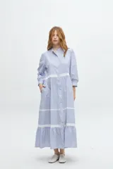 Vestido camisero midi color beige a rayas verticales, con cuello mao, mangas 3/4 abullonadas y festones de algodón en el cuerpo. Cierre frontal con botones.