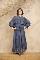 Conjunto azul con estampado floral negro, compuesto por una camisa de mangas largas con volados y una falda larga.