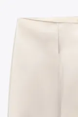 Pantalón de vestir color crema, de tela satinada, tiro alto y corte palazzo.