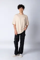 Remera blanca de corte oversize con mangas cortas y cuello redondo. Estampado pequeño en el frente con letras verdes.