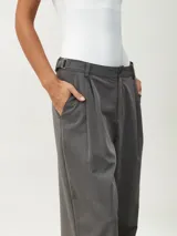 Pantalón gris oscuro de vestir con pinzas, corte amplio y tiro alto.