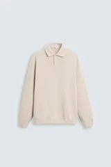 Polo color beige de manga larga, corte regular fit, confeccionado en tejido de algodón con elasticidad y estructura. Cuello solapa con cierre frontal de botonadura y acabados con rib.