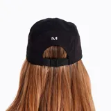 Gorra negra de trail running con estampado frontal reflectante, elástico en 4 direcciones, panel de malla transpirable, ajuste trasero, visera plana y estructura ligera y ajustable.