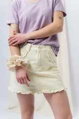 Minifalda de denim color crema con volados en los bolsillos delanteros y en el ruedo.